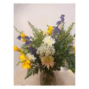Colourful Calypso bouquet of freesias, chrysanthemums and delphiniums framed by fresh green ferns.
