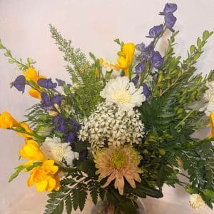 Calypso bouquet with freesias, chrysanthemums, delphiniums and ferns in yellow, purple and white.